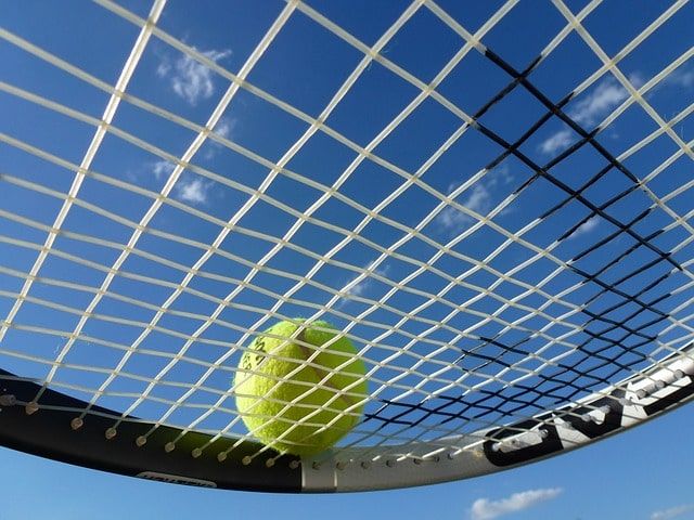 Tennis ball on racquet with blue sky
